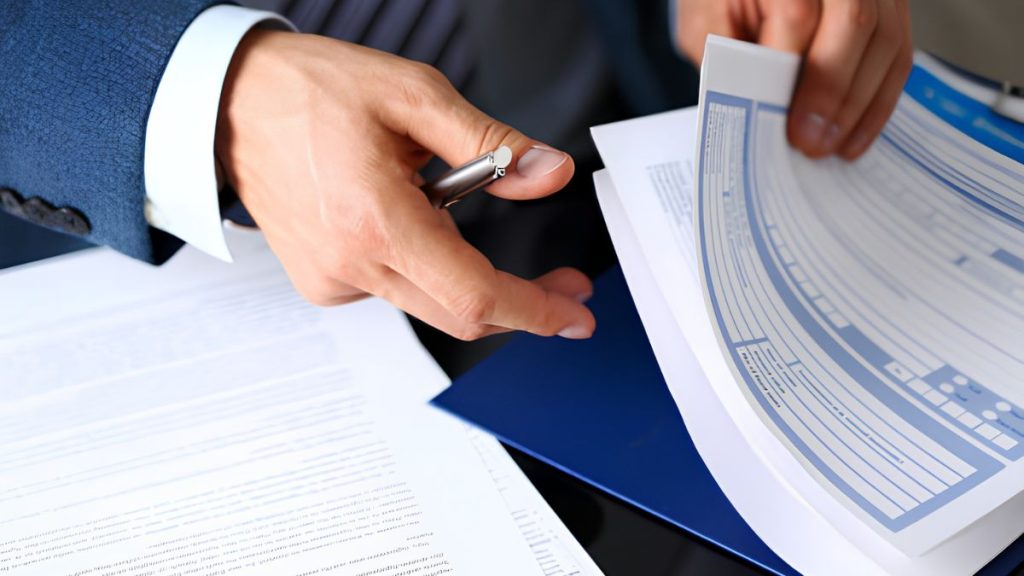 Businessperson in a suit reviewing documents, with a pen and a circular chart on the desk.