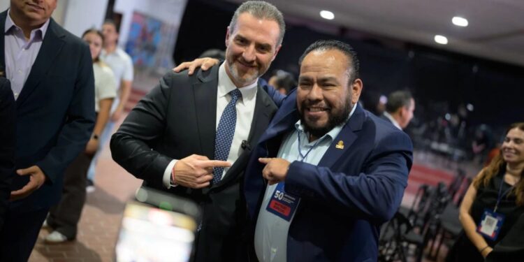 adrian-de-la-garza-monterrey - LA VISION 360 Two suited men smiling and posing together at an event, one with his arm around the other’s shoulder while they point at each other in agreement.